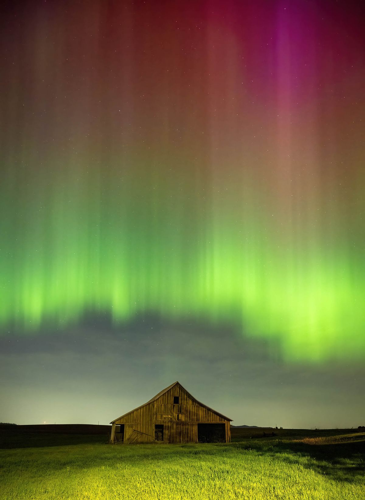 Charged particles spewed from the sun during a solar storm, make a colorful light display in the sky above a barn in Spangle on May 10.  (COLIN MULVANY/THE SPOKESMAN-REVIEW)