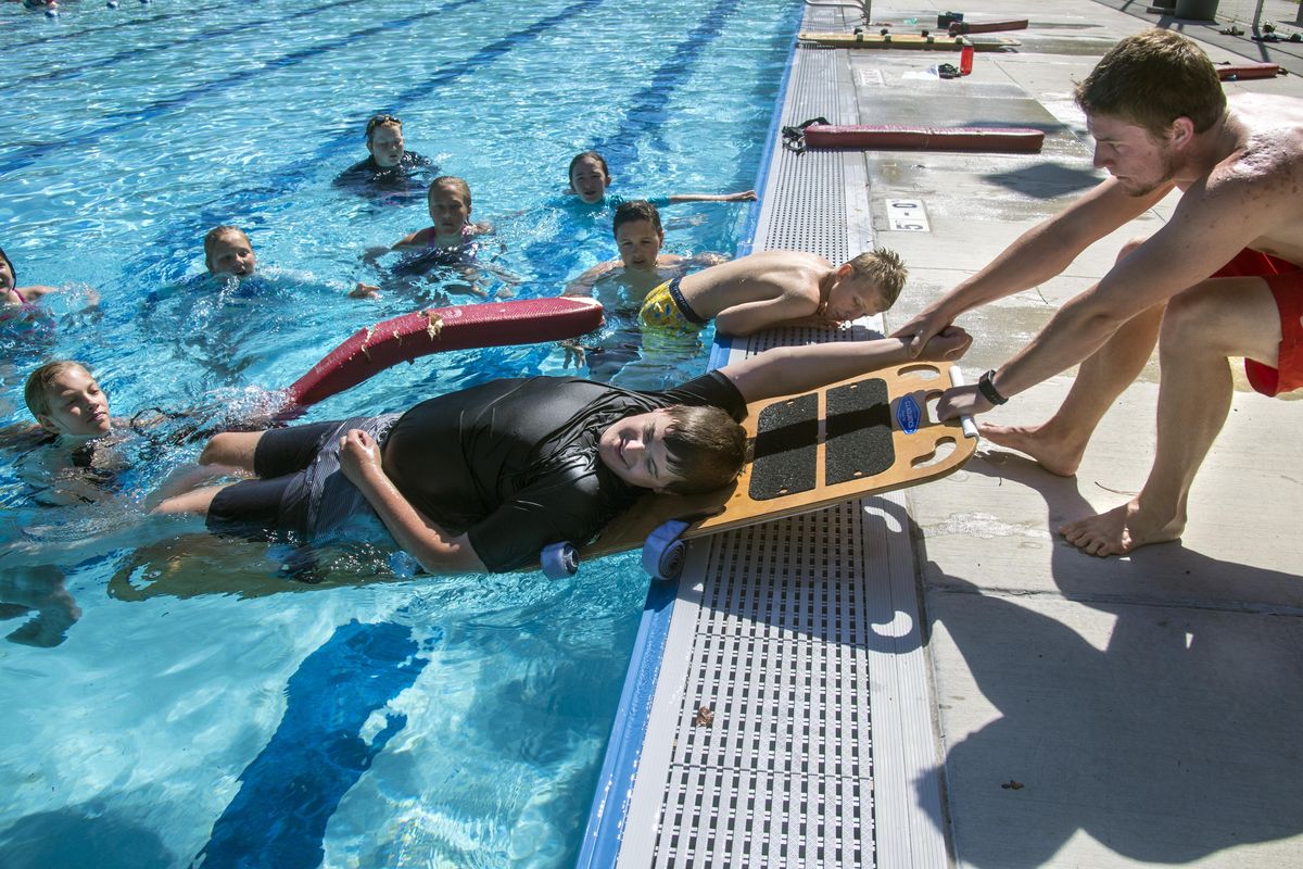 Swimming instructor Marty Waldrip, right, demonstrates to his class lifesaving measures being rendered to student Trevor Rubright, June 27, 2017, at Comstock Pool. (Dan Pelle / The Spokesman-Review)