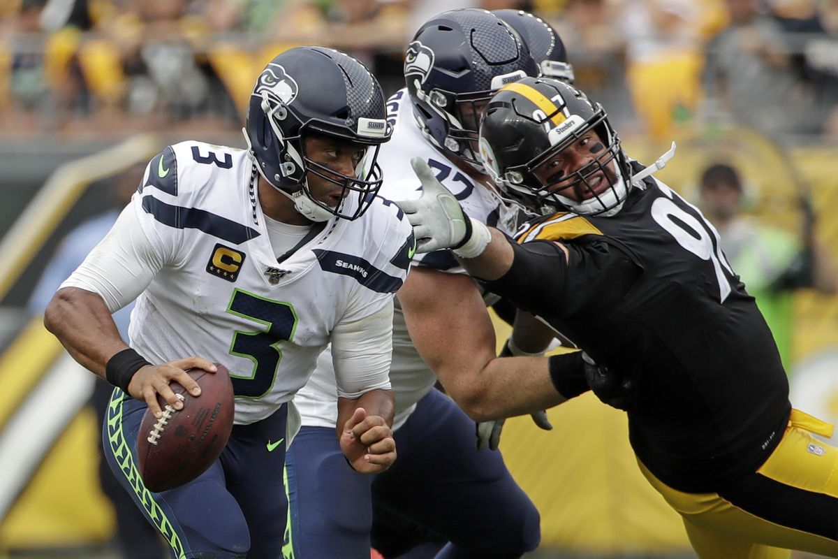 Seattle Seahawks quarterback Russell Wilson (3) scrambles past Pittsburgh Steelers defensive end Cameron Heyward (97), who is blocked by Ethan Pocic (77) during the second half of an NFL football game in Pittsburgh, Sunday, Sept. 15, 2019. The Seahawks won 28-26. (Gene J. Puskar / Associated Press)