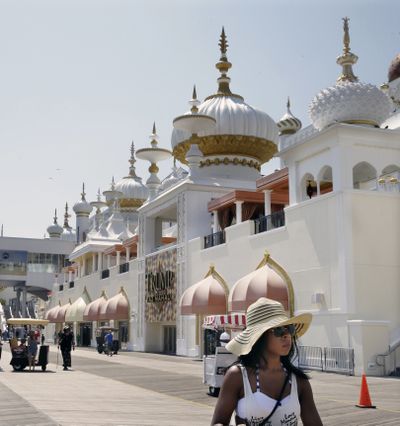 People walk along The Boardwalk past Trump Taj Mahal Casino Resort in Atlantic City, N.J., in July. The casino, struggling with a gambling downturn in New Jersey, faces closure. (Associated Press)