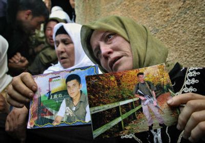 
Samiya Hammad holds photos of her son Samer Hammad, a suicide bomber who blew himself up in Tel Aviv, Israel, as she sits outside the family house in the West Bank village of Arakeh on Monday. 
 (Associated Press / The Spokesman-Review)