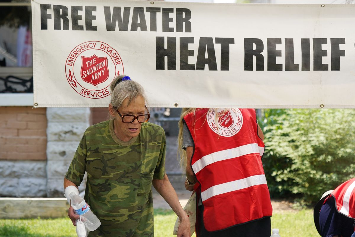 A pedestrian takes a bottle of water at a Salvation Army hydration station during a heatwave as temperatures hit 115-degrees, Tuesday, June 15, 2021, in Phoenix.  (Ross D. Franklin)