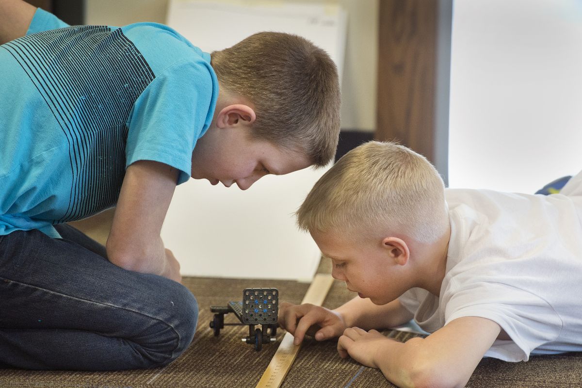 Samuel Cann and Preston Arrowsmith measure the distance traveled by their toy car.
