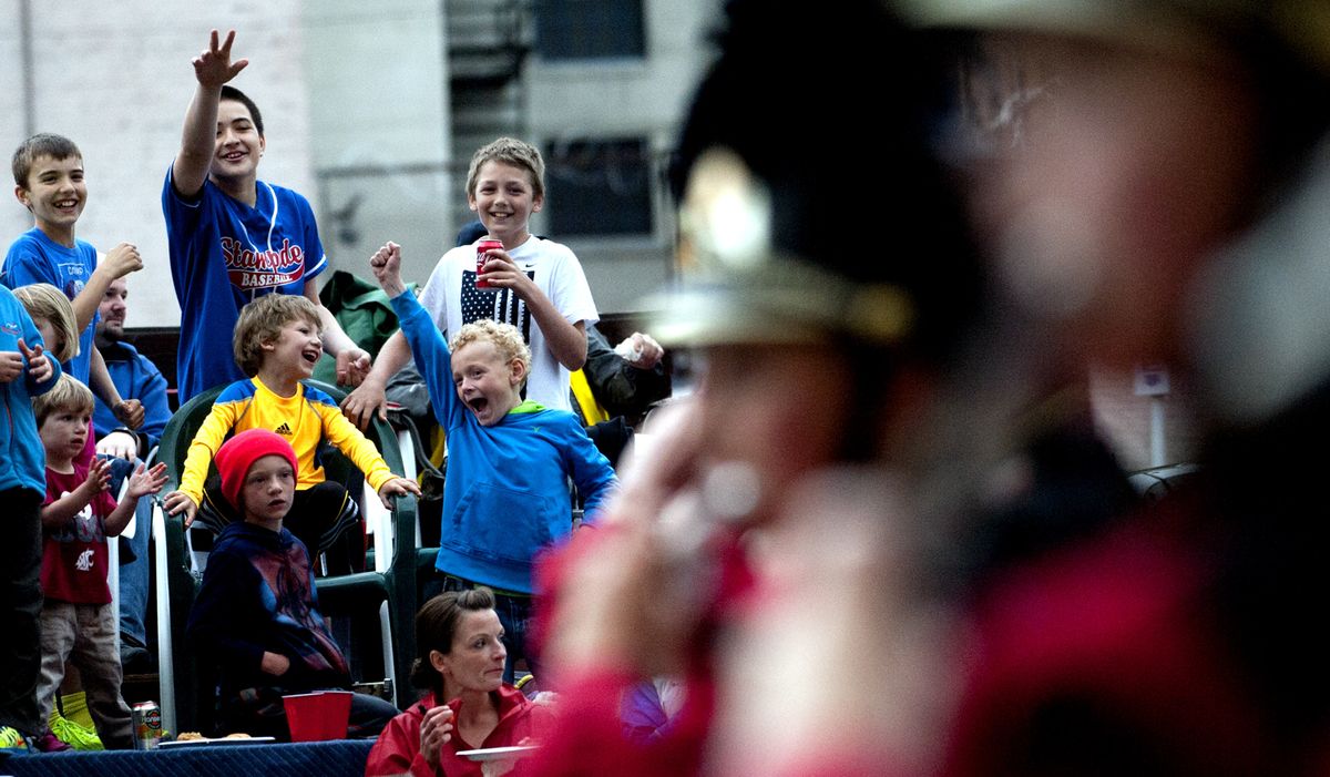 Spectators of all ages cheer on a marching band during Saturday’s 77th annual Armed Forces Torchlight Parade in downtown Spokane. (Kathy Plonka)