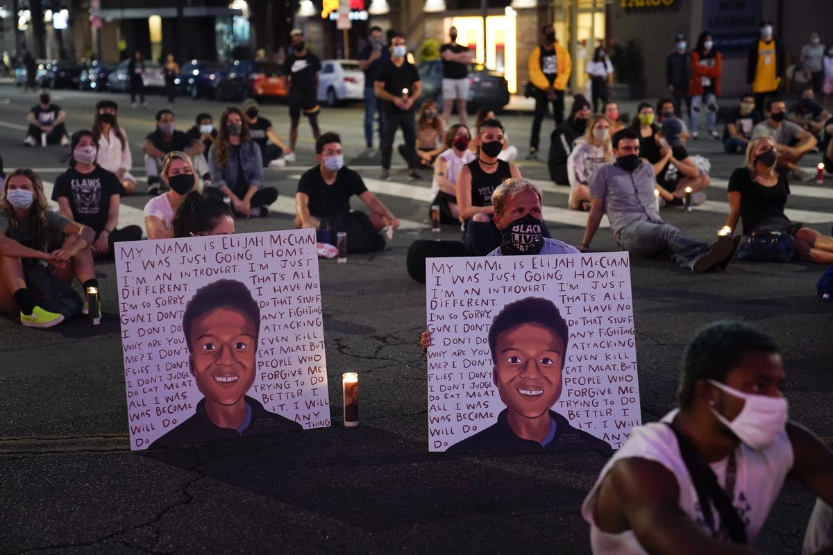 FILE - In this Aug. 24, 2020, file photo, two people hold posters showing images depicting Elijah McClain during a candlelight vigil for McClain outside the Laugh Factory in Los Angeles. Colorado police reform advocates say the recent indictments of three suburban Denver police officers and two paramedics on manslaughter and other charges in the death of Elijah McClain could be a pivotal step toward meaningful accountability.  (Jae C. Hong)