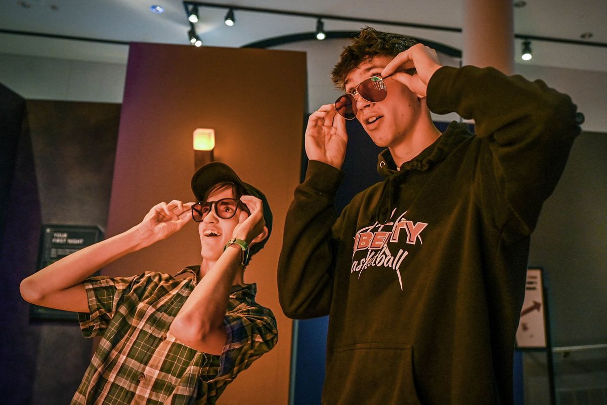 Joshua Domrese, left, and his twin brother, Thomas, 17, marvel at the colors they see at a orange-colored lava display during a demonstration of EnChroma glasses for color-blind visitors Thursday at the Northwest Museum of Arts and Culture.  (DAN PELLE/THE SPOKESMAN-REVIEW)