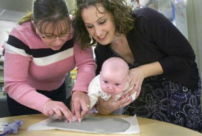 
Kathy Taylor, left, works with Andrea Thomas to make a casting of the hand and foot of her baby, Keegan. 
 (Christopher Anderson / The Spokesman-Review)