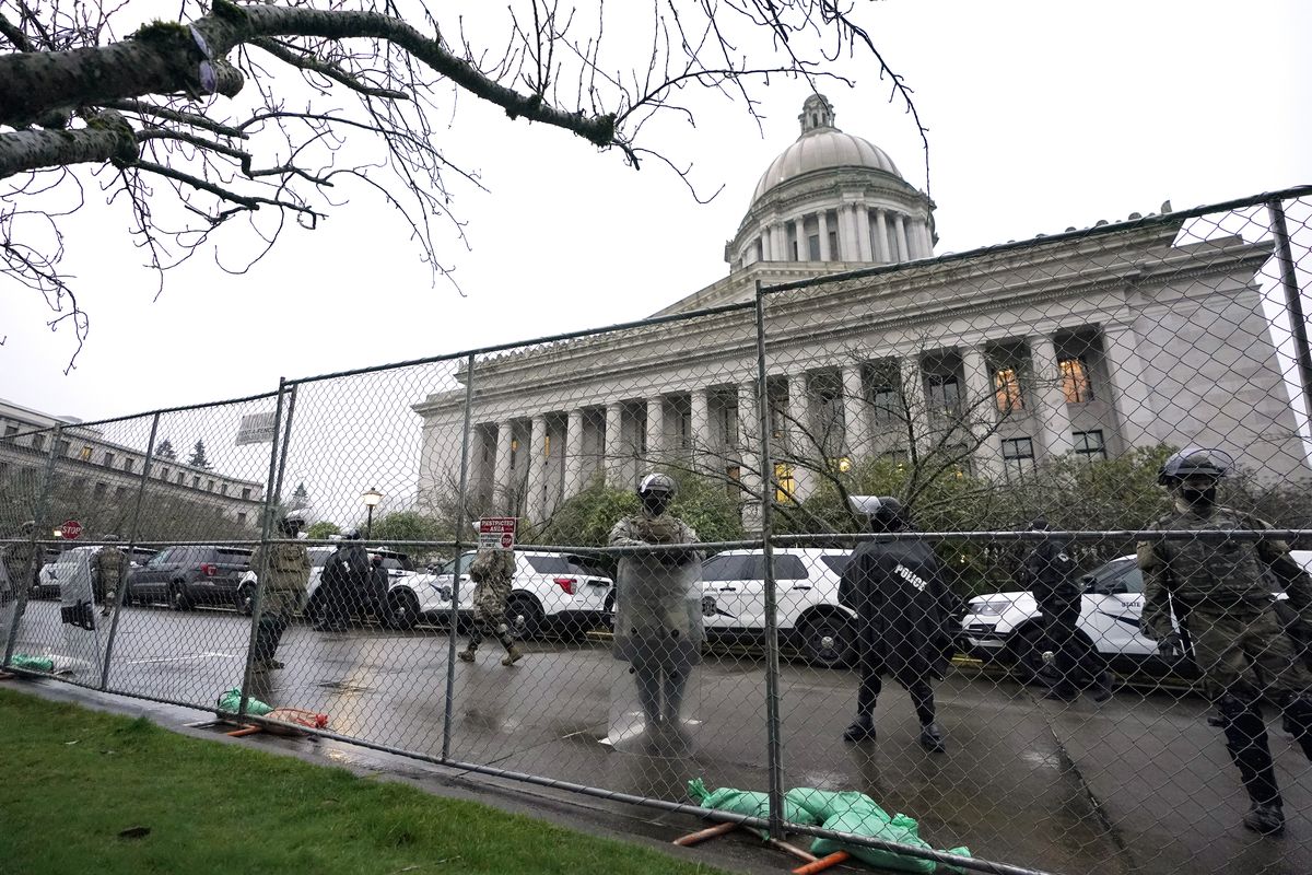 Members of the Washington National Guard stand near a fence surrounding the Capitol in anticipation of protests Monday, Jan. 11, 2021, in Olympia, Wash. State capitols across the country are under heightened security after the siege of the U.S. Capitol last week.  (Ted S. Warren)