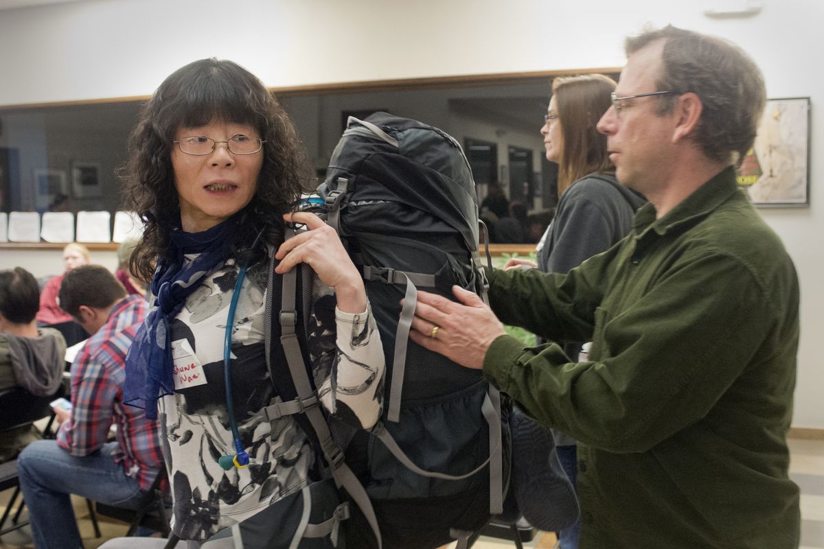 Shuwen Wang, left, tries on the backpack of Chuck Huber, right, at the second session of the Spokane Mountaineers backpacking class at the Mountain Gear headquarters. (Jesse Tinsley)