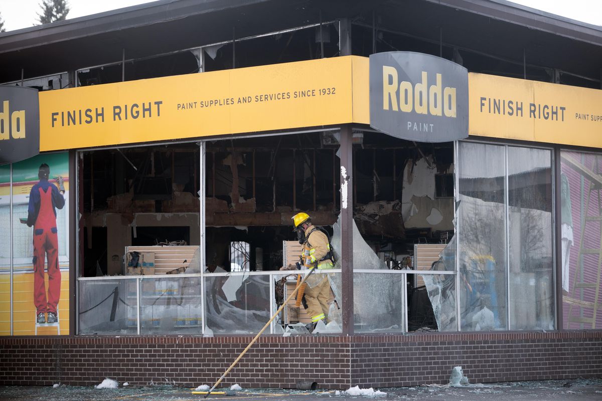 At the Rodda paint store at 6818 E. Sprague Ave. in Spokane Valley, a firefighter picks up fire equipment, Monday, Feb. 18, 2018, after a devastating fire, fought Sunday evening in the bitter cold. The building was fully involved when firefighters arrived. (Jesse Tinsley / The Spokesman-Review)