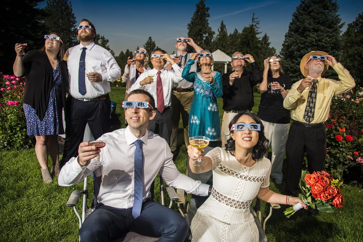 After their wedding ceremony, groom and bride, Nathan Mauger, Connie Young with family and friends, toast the solar eclipse from the Rose Garden in Manito Park, Mon., Aug 21, 2017, in Spokane, Wash. (Colin Mulvany / The Spokesman-Review)