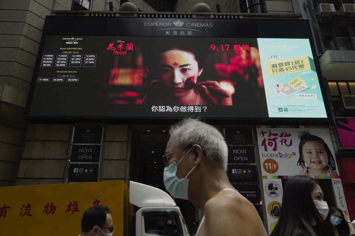 FILE-In this Thursday, Sept. 17, 2020, file, People walk past a huge TV screen showing movie listings "along a downtown street in Hong Kong. Hong Kong censors now have the power to ban films that endanger national security, prompting concerns that freedom of expression is being further curtailed in a city once known for its vibrant arts and film scene.  (Vincent Yu)