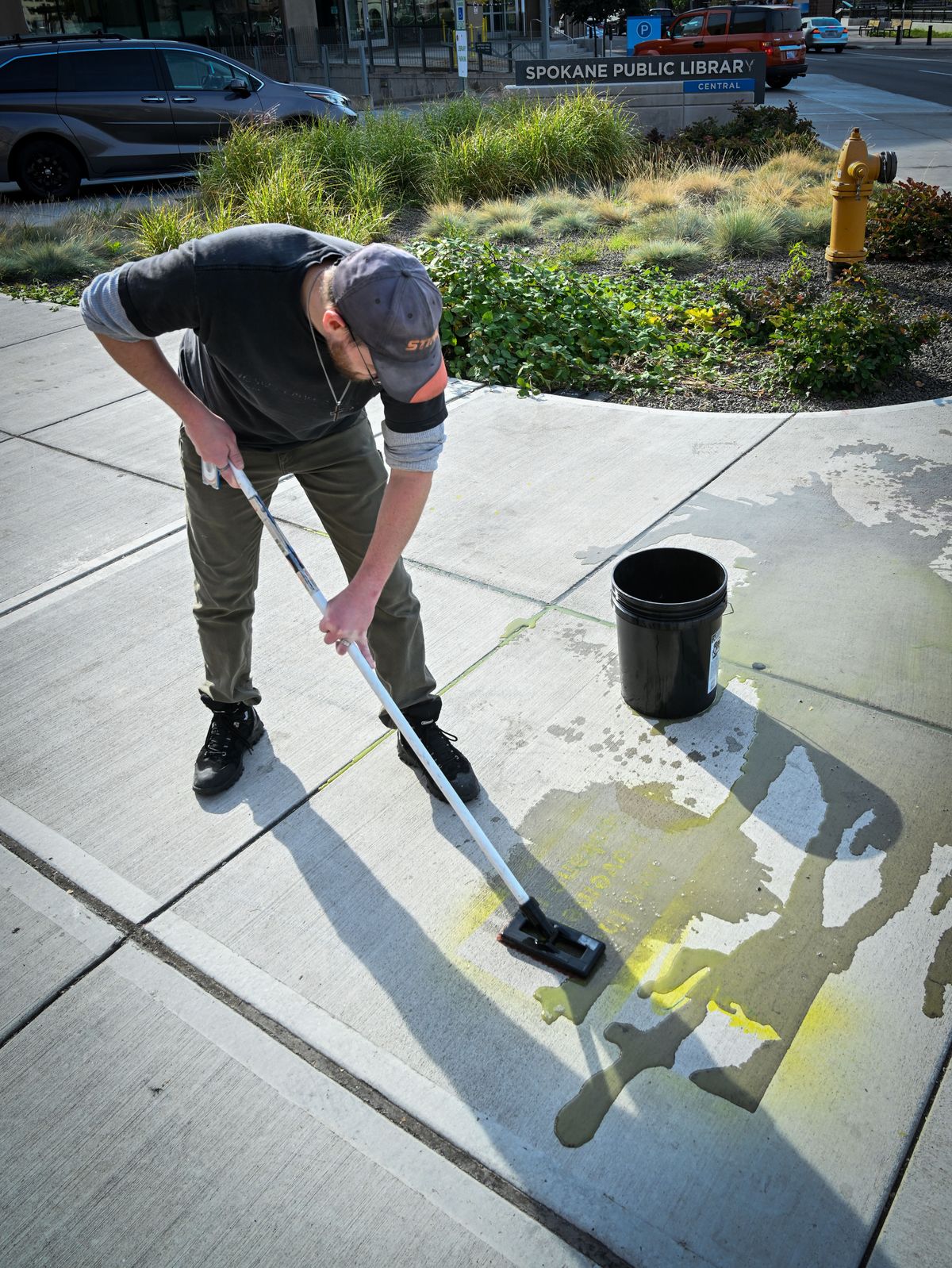 Keith Ritter, head custodian at the downtown Central Library, scrubs off one of a dozen “Join the Movement” stenciled graffiti on the sidewalk round the library. ‘They come up with soap and water, said Ritter.  (COLIN MULVANY/THE SPOKESMAN-REVIEW)