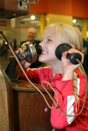 In this April 24, 2010 photo, Tamera O'Leary, 7, talks to a telephone operator on a 1904 silver dollar pay phone during the Hands on History event at the Holiday Village Mall in Havre, Mont. (Nikki Carlson / Havre Daily News)