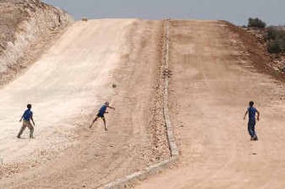 Palestinian children play ball at the site where Israel started building several months ago its separation barrier in the outskirts of the West Bank village of Biddu, north of Jerusalem.
(Associated Press / The Spokesman-Review)