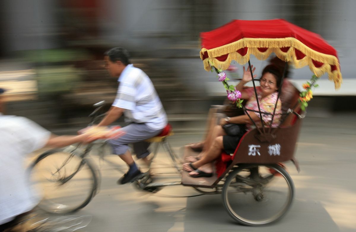 Beijing tourists get a ride on a pedicab through a hutong, or alley. (Associated Press / The Spokesman-Review)