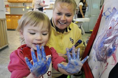 Sheri Sibley, a toddler teacher at Future Generations Children’s Center in Nine Mile Falls, helps 2-year-old Ashley Maggard with her finger-painting project Friday. Leanna Law, Sibley’s employer, is among local child care owners backing a plan in Olympia to unionize workers.  (Dan Pelle / The Spokesman-Review)
