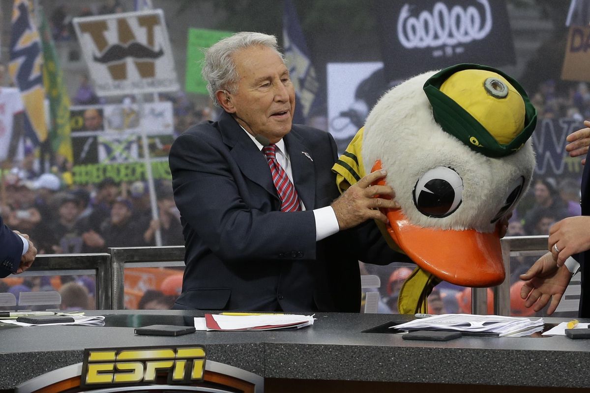 ESPN College GameDay host Lee Corso puts on the mascot head of the Oregon Ducks as he makes his prediction of an Oregon win over Washington  on Oct. 12, 2013, during College GameDay’s broadcast from Red Square on the University of Washington campus in Seattle. (Ted S. Warren / AP)