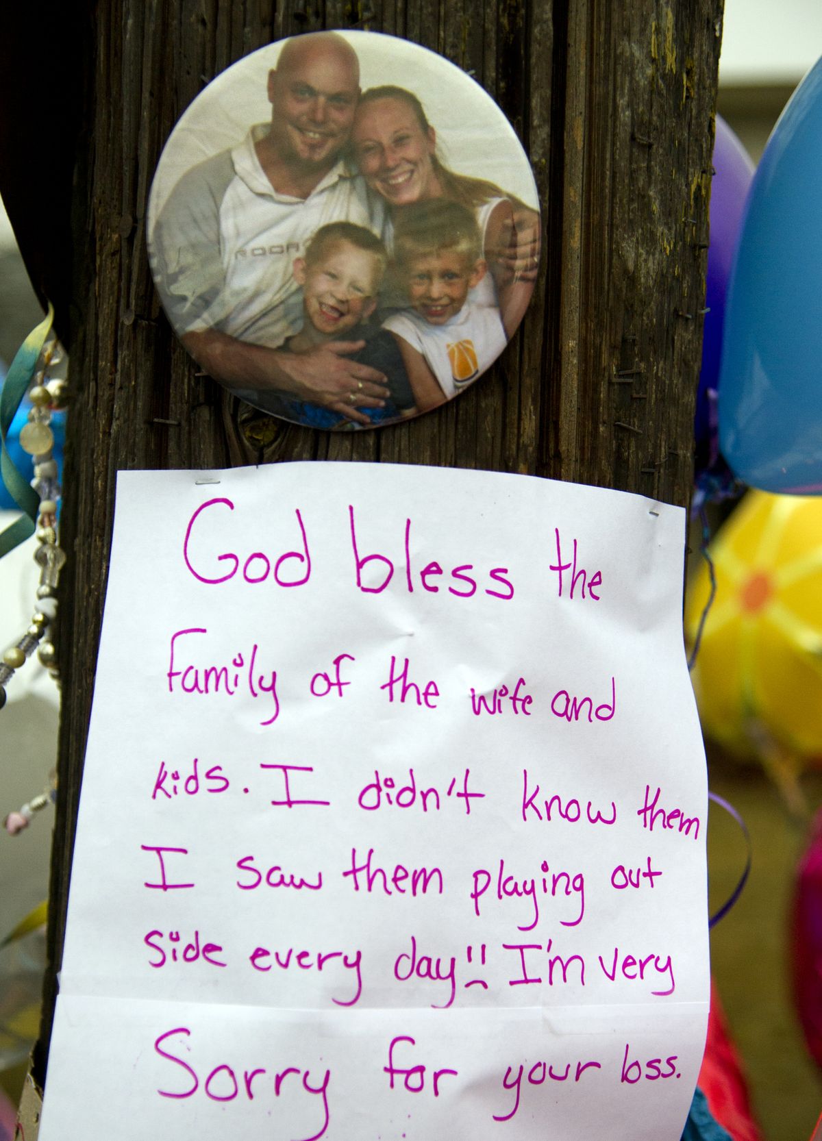 A photo of Nick Ader, his wife Tracy and their two sons is the centerpiece to a growing memorial to the murdered members of the family at the intersection of Heroy Avenue and Whitehouse Street. (Colin Mulvany / The Spokesman-Review)