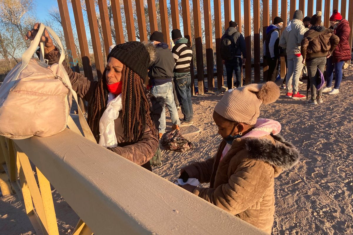FILE - A Cuban woman and her daughter wait in line to be escorted to a Border Patrol van for processing in Yuma, Ariz., Sunday, Feb. 6, 2022, hoping to remain in the United States to seek asylum. A federal appeals court has upheld sweeping asylum restrictions to prevent spread of COVID-19 but restored protections to prevent migrant families from being expelled to their home countries without a chance to plead their cases.  (Elliot Spagat)