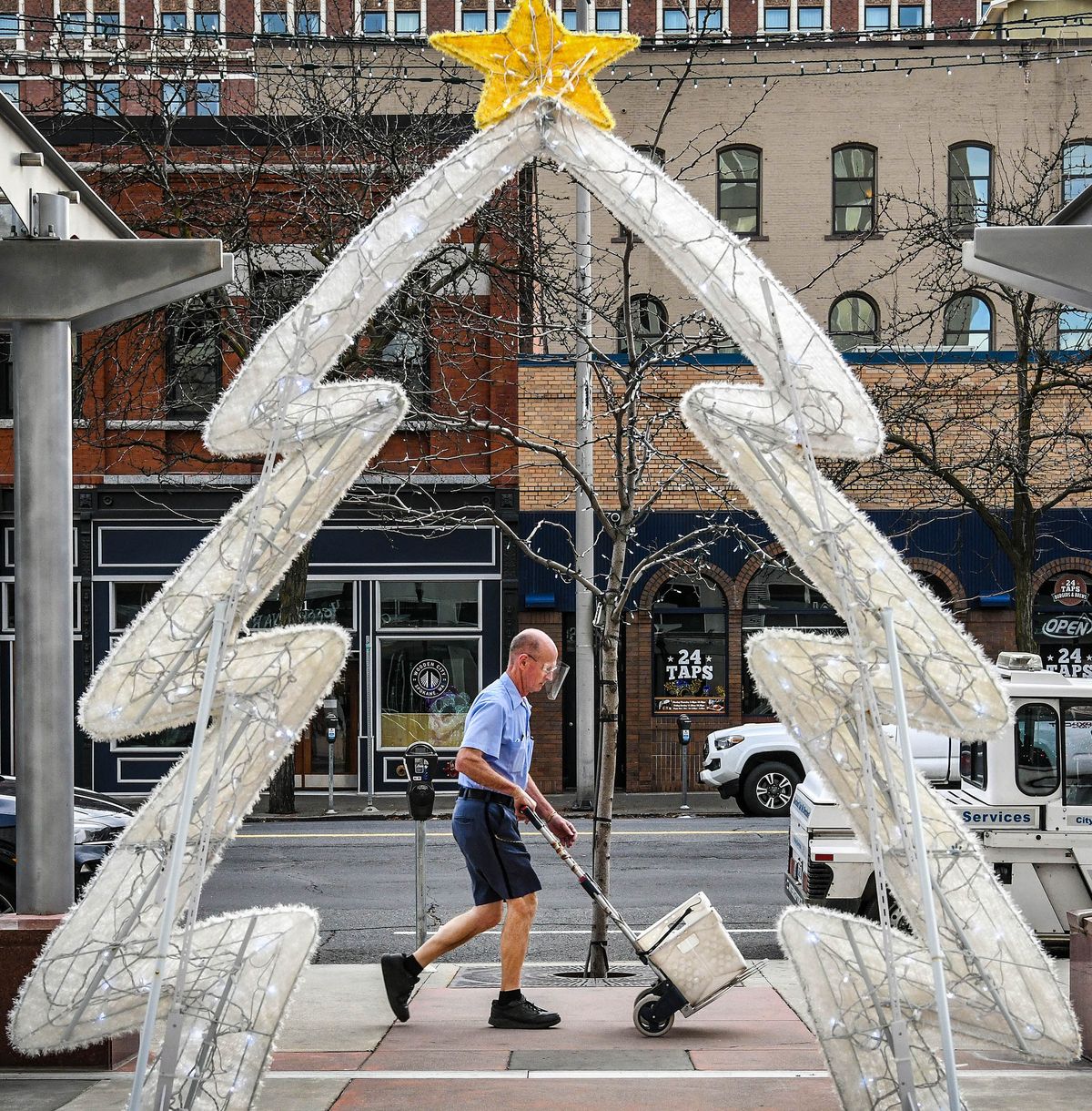 Letter carrier Pete Michalowicz makes his way past the Lincoln Building’s holiday decoration and back to the downtown post office after working his route wearing shorts as temperatures neared 60 degrees Wednesday afternoon in Spokane. Michalowicz said he has been dressed like this since 1999.  (DAN PELLE/THE SPOKESMAN-REVIEW)