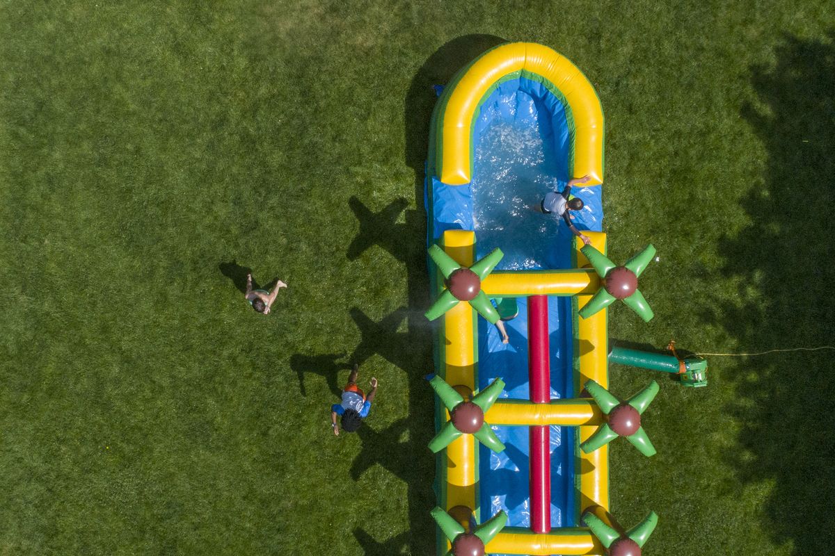 A 25-foot inflatable palm tree Slip ‘N Slide helps neighborhood kids cool down in South Orange, N.J., May 20, 2021. According to the Pool & Hot Tub Alliance, pool sales rose by more than 20% in 2020, although many families alternatively turned to water bounce houses, backyard splash pads, Slip ‘N Slides and other water-filled items to stay cool at home.  (TONY CENICOLA/The New York Times)