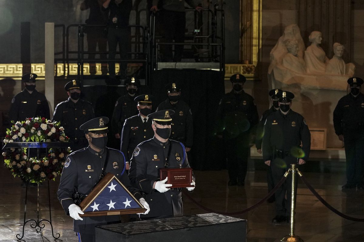 An honor guard places an urn with the cremated remains of U.S. Capitol Police officer Brian Sicknick and folded flag on a black-draped table at center of Capitol Rotunda to lie in honor Tuesday, Feb. 2, 2021, in Washington.  (Salwan Georges/The Washington Post via AP)