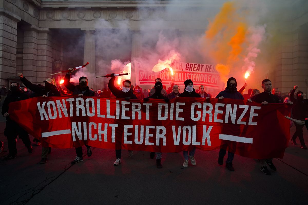 Demonstrators shout slogans and light flares during a demonstration against measures to battle the coronavirus pandemic in Vienna, Austria, Saturday, Nov. 20, 2021. Thousands of protesters are expected to gather in Vienna after the Austrian government announced a nationwide lockdown to contain the quickly rising coronavirus infections in the country. Banner reads: 