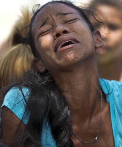 A relative grieves during the funeral of Alirio Duran, 25, at the Municipal Cemetery of Valencia, Venezuela, Friday, March 30, 2018. Weeping relatives arrived at the central cemetery on Friday carrying the caskets of many of the 68 victims who were killed in a police station fire to place them in a freshly dug mass tomb. (Ariana Cubillos / Associated Press)