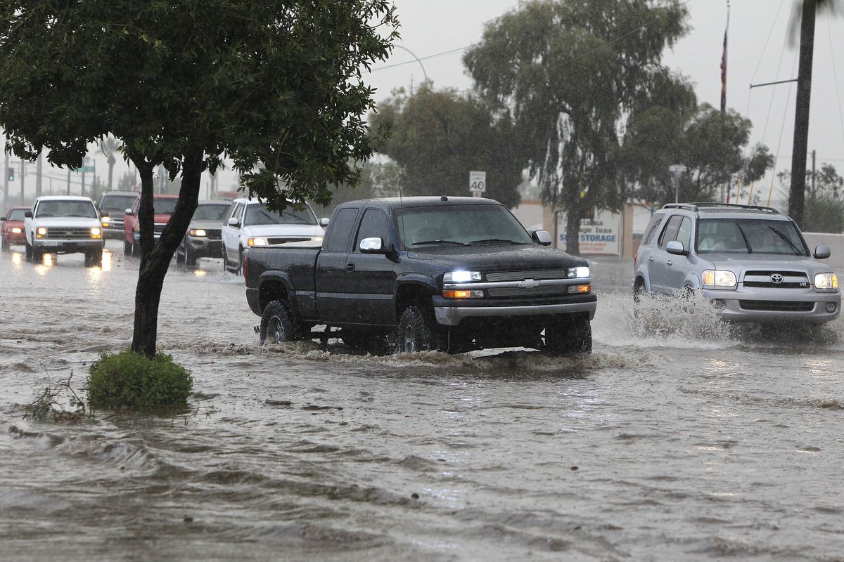 Traffic tries to navigate a flooded street after violent storms passed through Tuesday in Phoenix.  (Associated Press)
