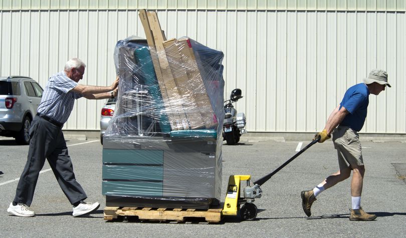 Marvin Gee, of Spokane, right, and Paul Eirich, of Tennessee, move a pallet of medical equipment at Spokane County Fair and Expo Center on Friday, preparing for the Your Best Pathway to Health clinic. (Dan Pelle)