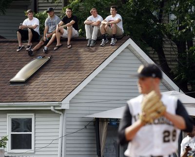 Spectators line a rooftop on a house across the street as Vanderbilt pitcher Grayson Garvin readies his windup during the first inning of their NCAA college baseball tournament regional game against Louisville in Louisville, Ky., Monday, June 7, 2010. (Ed Reinke / Associated Press)