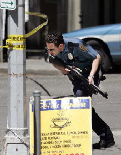
A Seattle police officer runs toward the Federal Courthouse in downtown Seattle on Monday. A man carrying what appeared to be a hand grenade was shot to death in the lobby of the building after he walked inside and made threats, police said.
 (Associated Press / The Spokesman-Review)