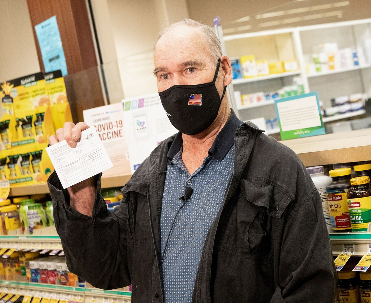 Meals on Wheels volunteer Tom Lawson holds up his vaccination card after receiving the first dose of the Pfizer vaccine while speaking at a presser regarding the working relationship between Safeway and Albertsons stores with Meals and Wheels of Greater Spokane County on Wednesday, March 3, 2021 at the Northwest Blvd. Safeway in Spokane. The stores are setting aside blocks of appointments for Meals on Wheels seniors to receive the Covid-19 vaccine.  (Libby Kamrowski/ THE SPOKESMAN-R)