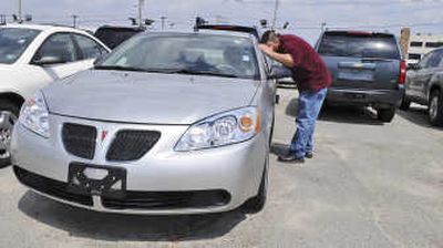 Matt Aquano looks at a Pontiac G6  at a car dealership in Danvers, Mass., on Thursday. Aquano is planning to trade in his Chevy Trailblazer and purchase a 4-cylinder car that gets better gas mileage.  In the background are other sport utility vehicles that were traded in at the dealership. Associated Press
 (Associated Press / The Spokesman-Review)