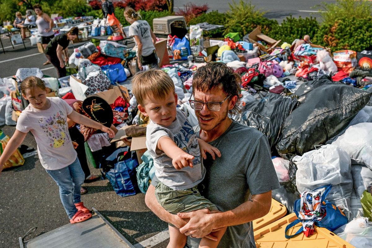 Scott Bennett and his son Logan 3, search through donated free items in the parking lot of Safeway in Spokane on Monday, August 3, 2026. The family had to evacuate from the Five Mile area on Saturday due to fire danger. Girl Scout Troup 2454 leader Desiree Dean organized the event.  (Kathy Plonka/The Spokesman-Review)