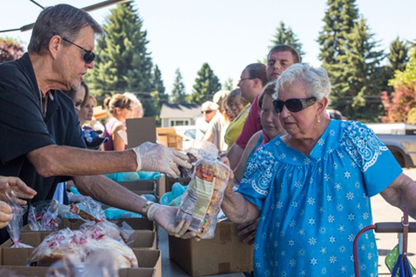 Second Harvest Mobile Food Bank volunteer Lowell Nelson hands Arlene Nelson of Coeur d'Alene a bag of bagels at the food bank's distribution on Tuesday at Christ the King Lutheran Church. 