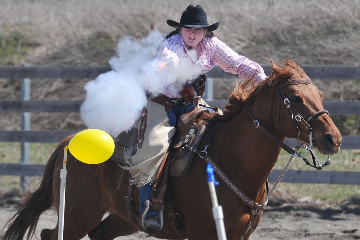 Alisa Peters, 12, leans out from her horse, Gator, and fires at a balloon on a pole during mounted shooting practice April 23. (Jesse Tinsley / The Spokesman-Review)