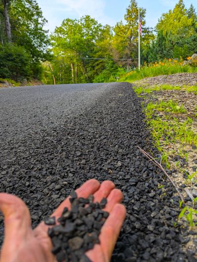 This rural road near my house was just coated with small stone chips embedded in a thin layer of asphalt cement. You can do the same thing on your driveway.  (Tribune Content Agency)