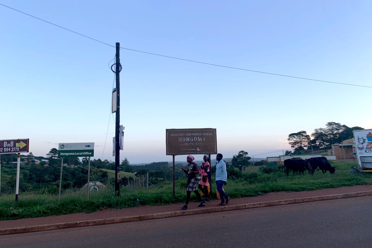 People walk past a sign marking the town of Nongoma in South Africa