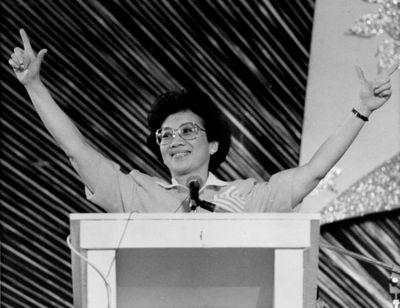 Then-Philippine President Corazon “Cory” Aquino flashes the “L” sign for Laban, meaning “Fight,” as she addresses  a crowd in Manila on Feb. 25, 1989.  (File Associated Press / The Spokesman-Review)