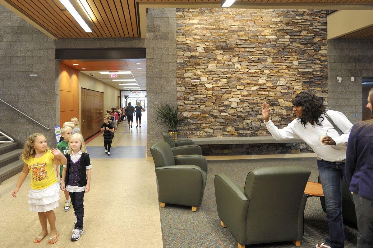 Paula Jenkins, right, waves to student Jaden Thompson, left, as Sue Davey’s first-grade class walks past the waiting area inside the new Westview Elementary School on Tuesday, the first day of classes. Jenkins has two children in the school. (Dan Pelle)