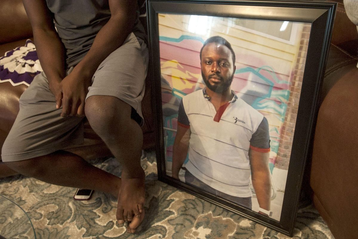Solomon Katumbi sits next to a photo of his brother, Paul, who died unexpectedly at the end of August during an interview on Monday, Sept. 23, 2019. Paul Katumbi was a kind of patriarch for the Katumbi family – 10 people who came to Spokane as refugees from Congo in 2015. (Kathy Plonka / The Spokesman-Review)