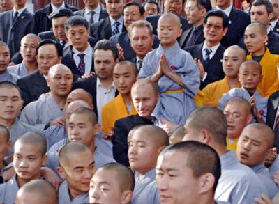 
Russian President Vladimir Putin holds a young monk on his shoulder after watching a demonstration of Shaolin Kung Fu in Shaolin Temple in central China's Henan Province.  Established about 1,500 years ago, Shaolin combines martial arts skill and Zen, a sect of Buddhism that utilizes long meditation sessions to purify the mind. 
 (Associated Press / The Spokesman-Review)