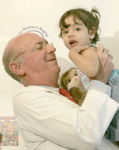 
Dr. Thomas Balkany carries 3-year-old Amina, of Iraq,  in Miami. Amina, who was born deaf, arrived July 30 to receive a cochlear implant that will allow her to hear. 
 (Associated Press / The Spokesman-Review)