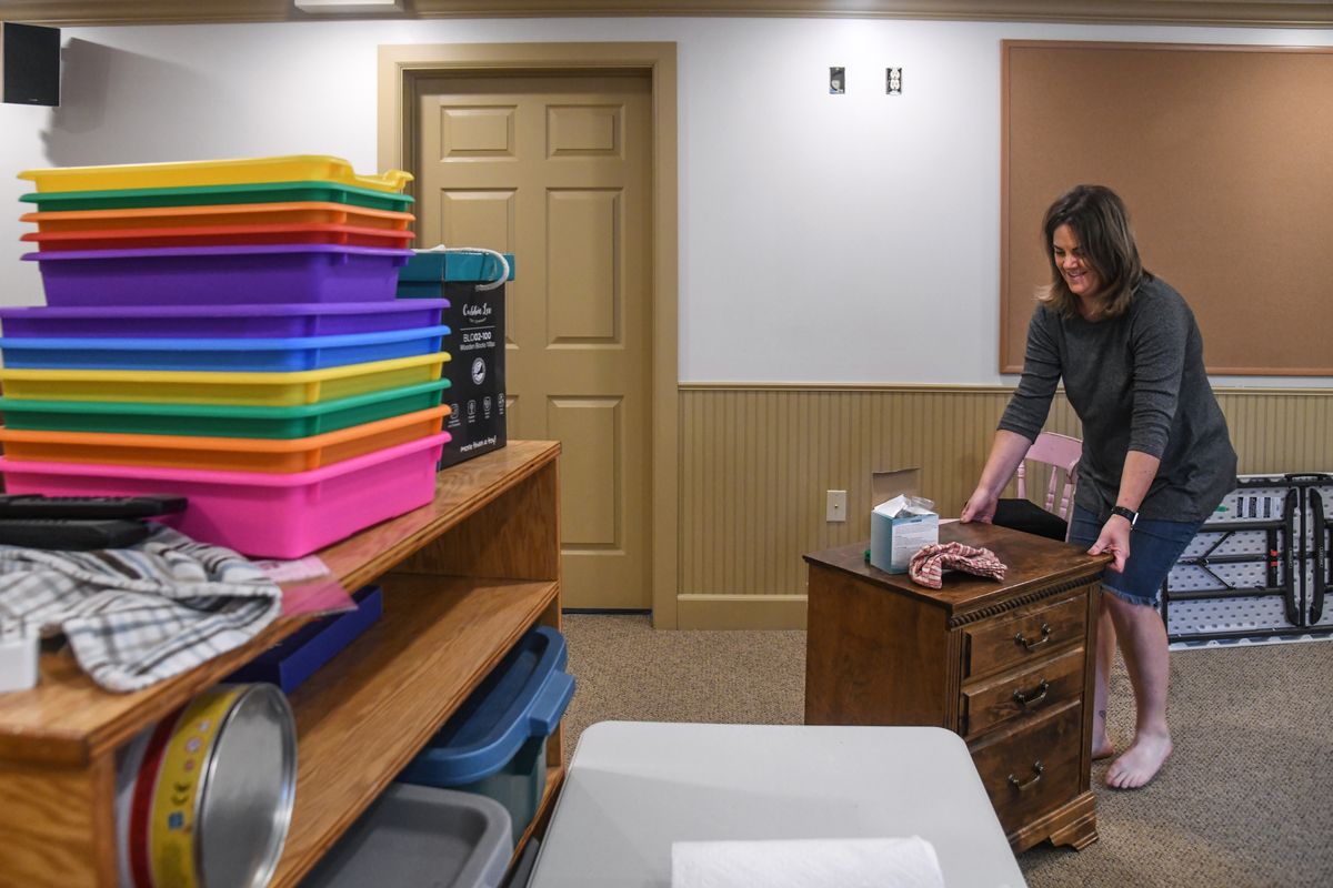 Teacher Chandra Burghart slides furniture into place as she sets up her classroom in Robyn McClain’s basement on Wednesday in Spokane.  (Dan Pelle/The Spokesman-Review)
