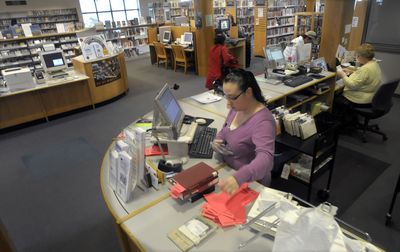 Christina York works behind the desk of the East Side branch of the Spokane Public Library on  Friday. The Spokane library system may be forced to cut 4 percent from its budget, and could compensate for the loss by closing a neighborhood branch.  (Christopher Anderson / The Spokesman-Review)