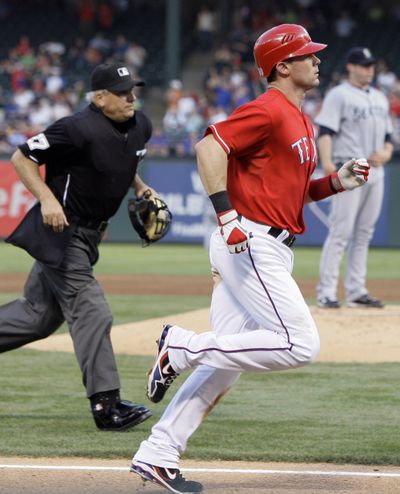 Texas Rangers' Michael Young, foreground, runs home as he is followed by home plate umpire Larry Vanover, left, following Young's solo home run off of Seattle Mariners' Ryan Rowland-Smith, background right. (Tony Gutierrez / Associated Press)