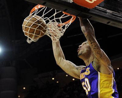 Lakers’ Robert Sacre dunks the ball against the Rockets in his first career start on Tuesday night. (Associated Press)