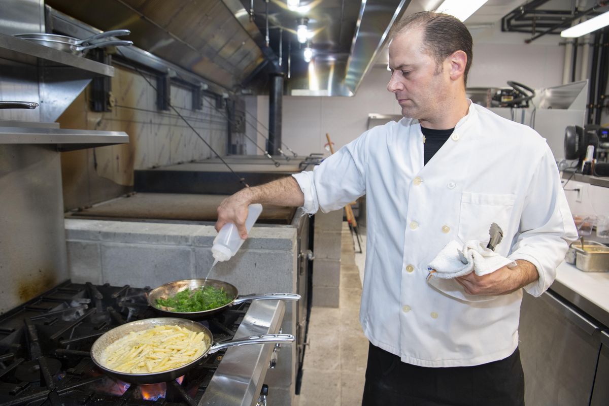 Chef Mike Jones, owner of Mizuna and Austin’s Live Fire Barbecue, prepares two side dishes - a creamy smoked Gouda mac and cheese and braised greens with bacon - to go with his smoked meats at his new restaurant in downtown Spokane. (Jesse Tinsley / The Spokesman-Review)